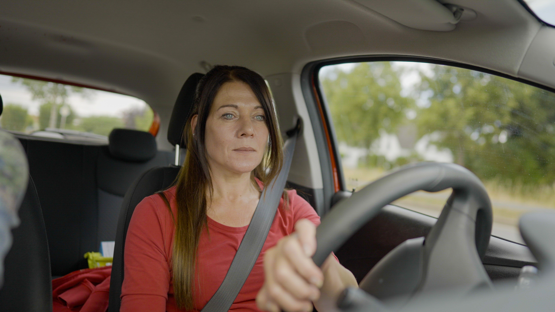 Mobile Pflege - Pflegekraft im Dienstfahrzeug unterwegs zu Patienten